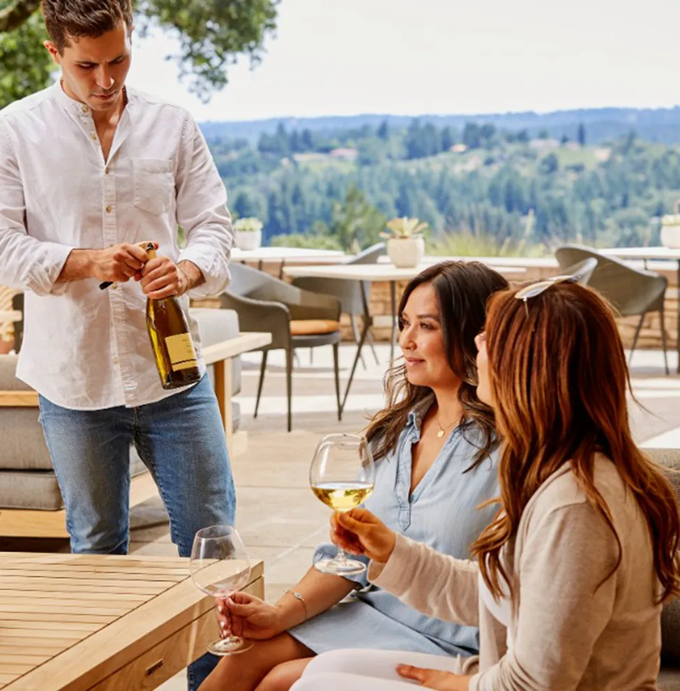 Two women being served white wine on the Gary Farrell patio