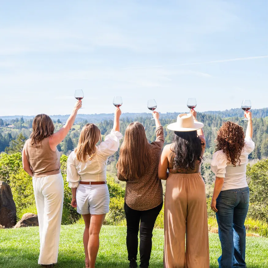 Five women looking towards the hills holding glasses of red wine