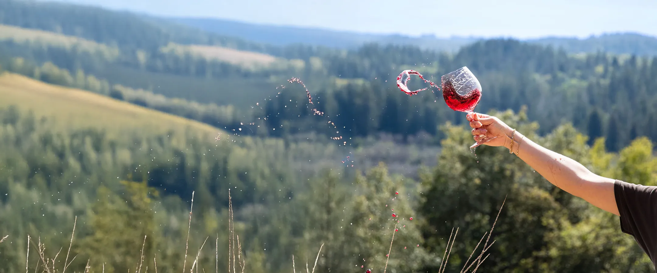 Woman holding a glass of red wine on a hill