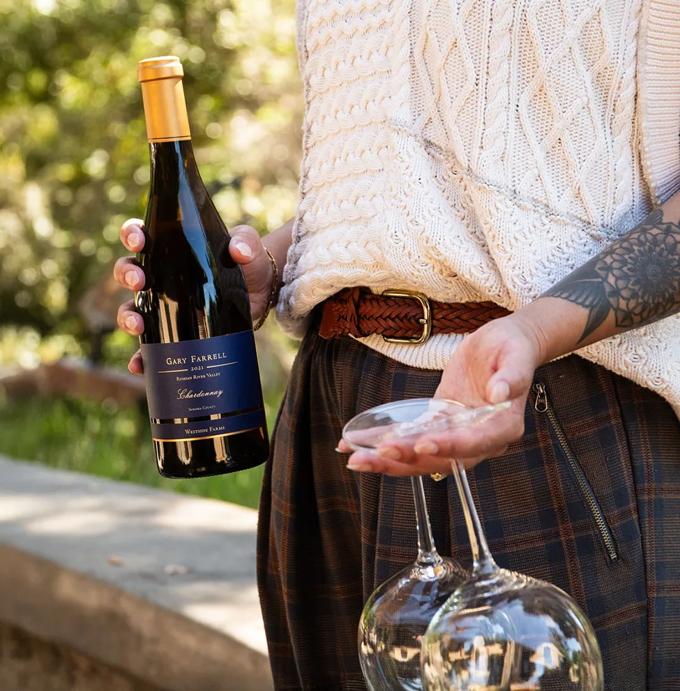 Woman holding a bottle of wine and two glasses