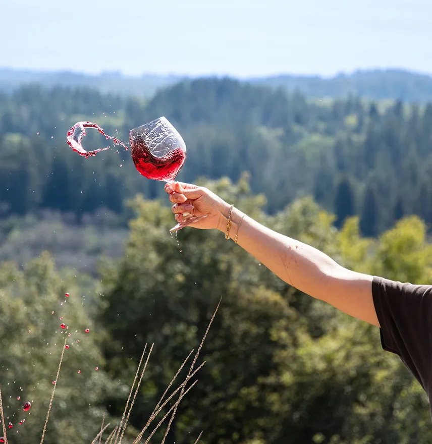 Woman holding a glass of red wine on a hill
