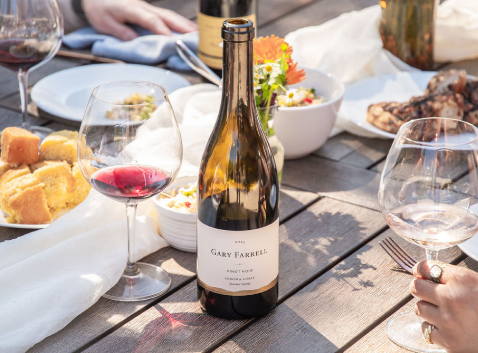 A bottle of Gary Farrell Pinot Noir on a table with wine glasses and snacks.