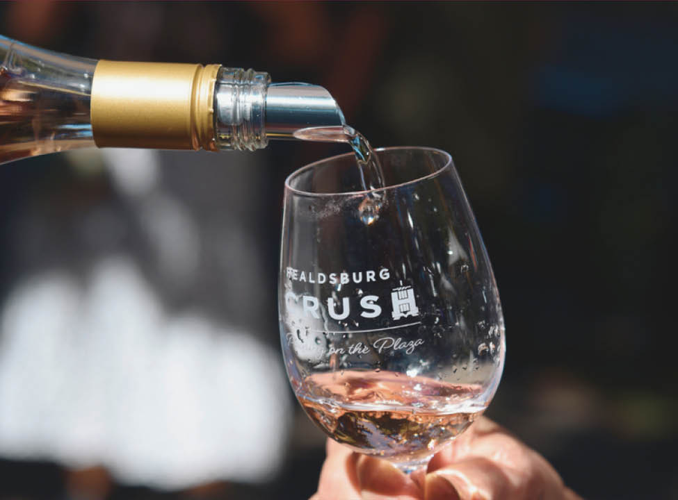 Pouring wine into a glass that says "Healdsburg Crush" on front.