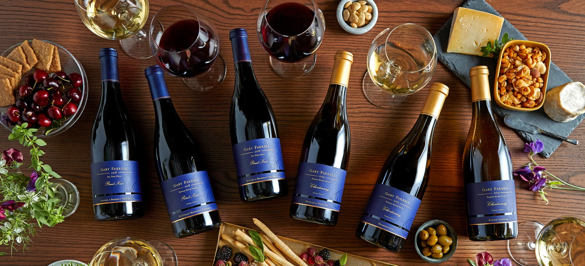 Assortment of Gary Farrell wine bottles on a table with glasses and food