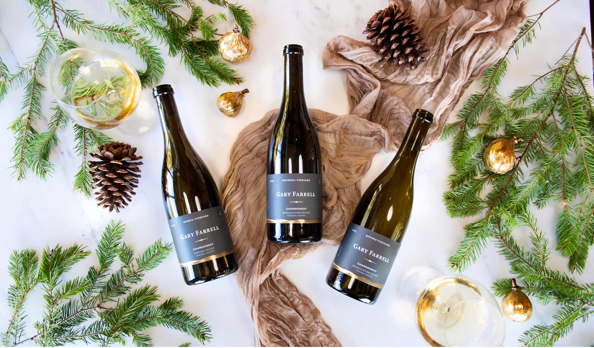 Gary Farrell Winery's Chardonnay Collection Holiday Gift Set displayed with cedar branches, wine glasses, and various festive decor.